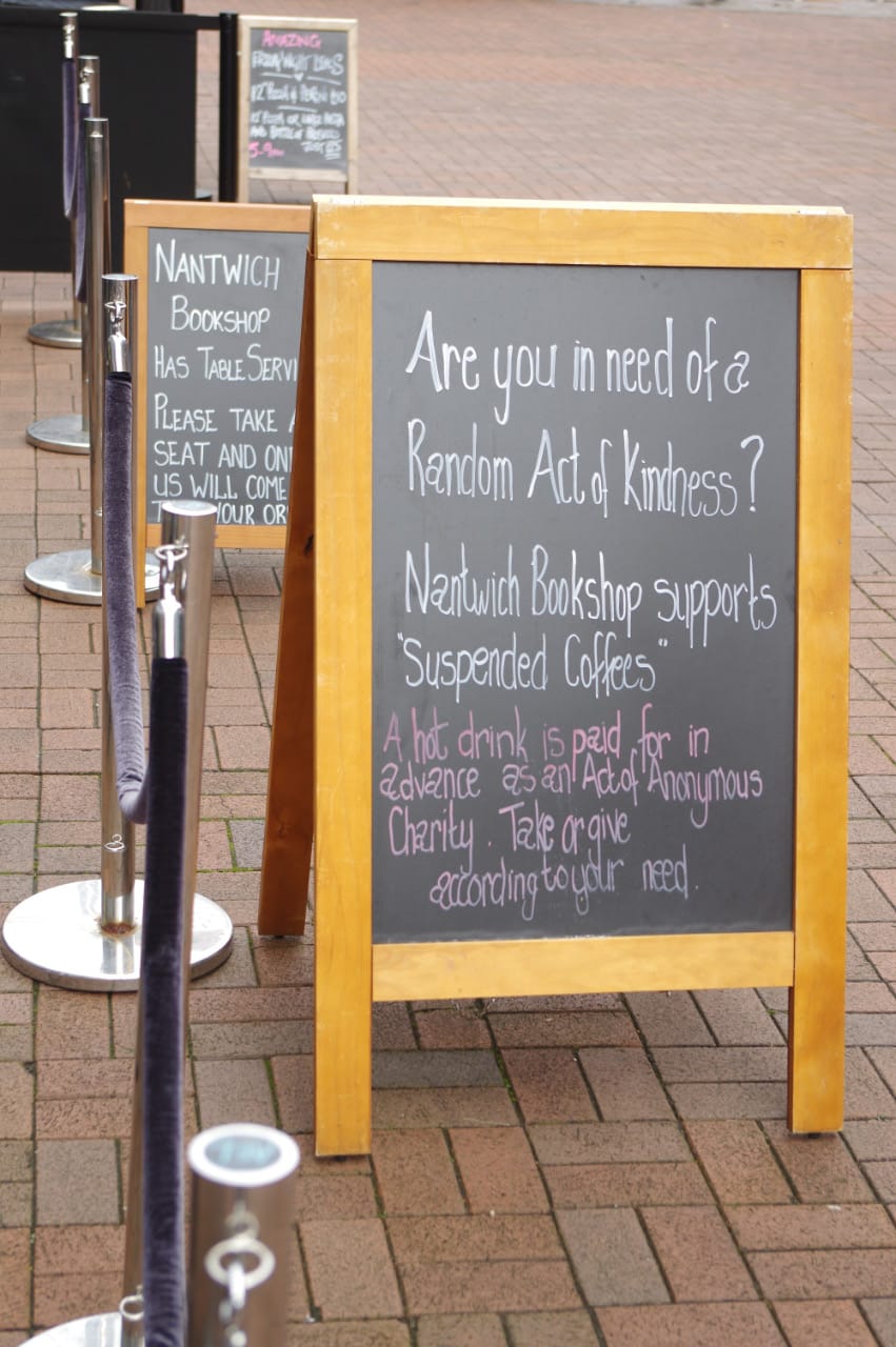 A sandwich board sign promoting free coffees paid for by strangers. 