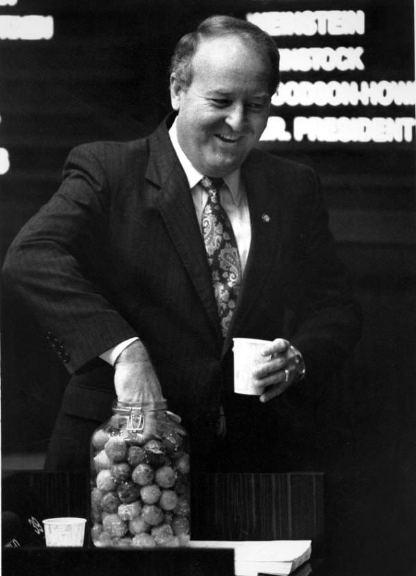 Senator Fred Dudley sticks his hand in a jar of donut holes. 