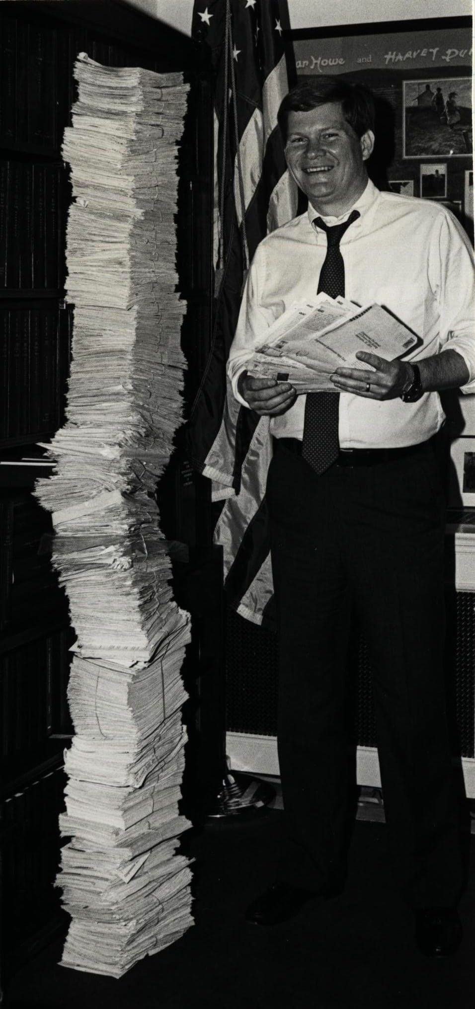 Congressman Tim Johnson standing next to a stack of constituent mail as tall as him. 